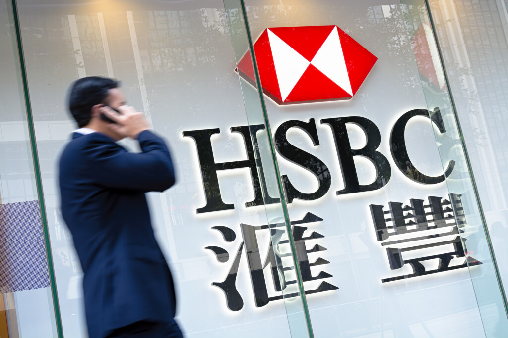 Hong Kong, Hong Kong SAR -November 17, 2014: Motion blured business man passing by an HSBC Bank sign in Hong Kong. HSBC Holdings plc is the world's third largest bank by assets.